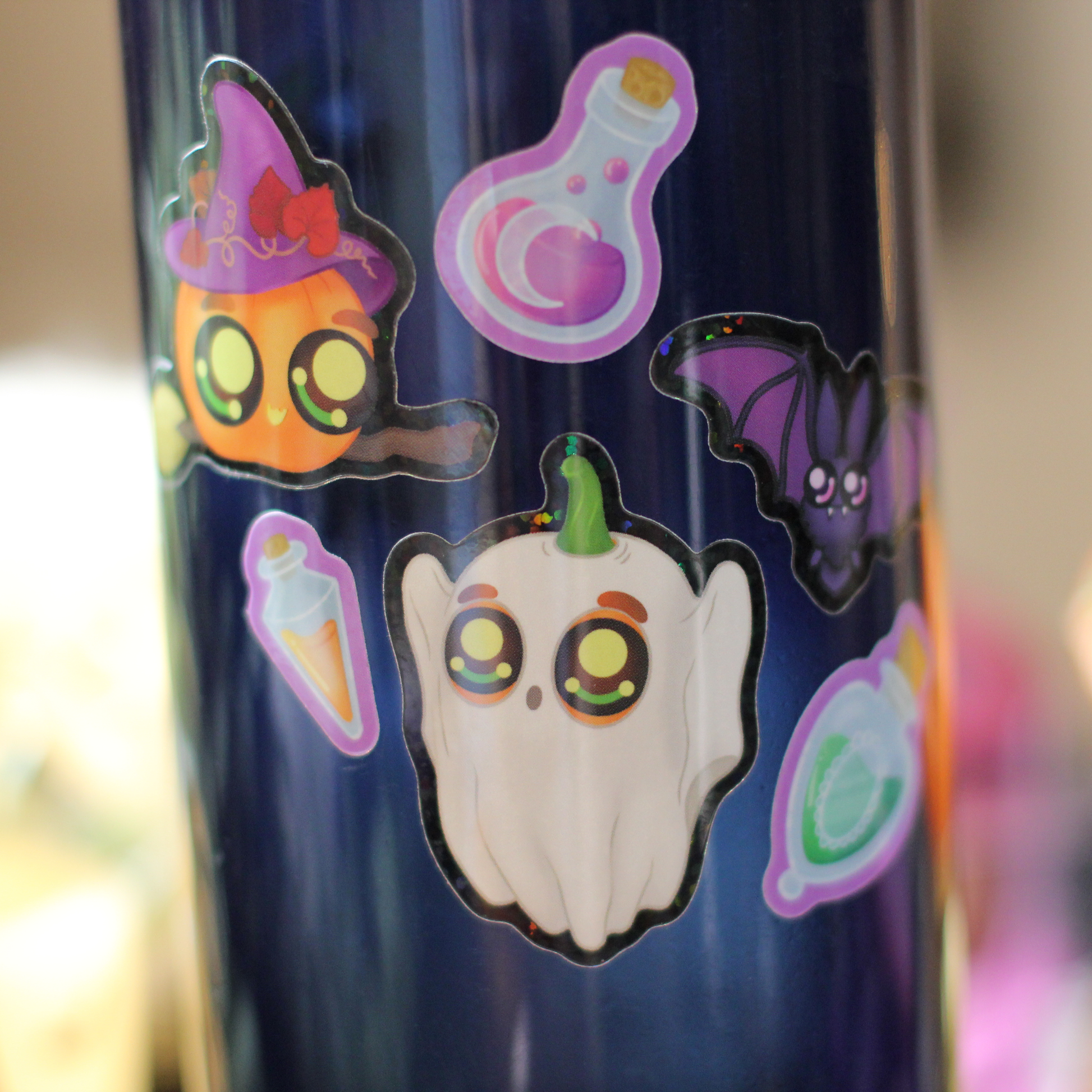 cute halloween stickers on navy water bottle, including ghost, pumpkin witch, bat, and potions
