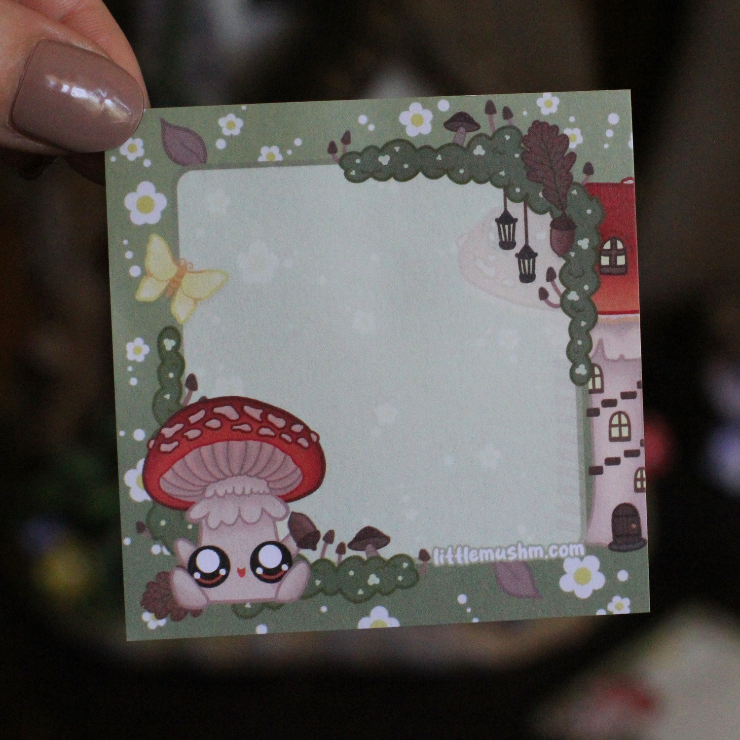 A sticky note with a green background featuring a cartoon mushroom character, flowers, and a small house. The text 'Little mushm' is visible at the bottom.